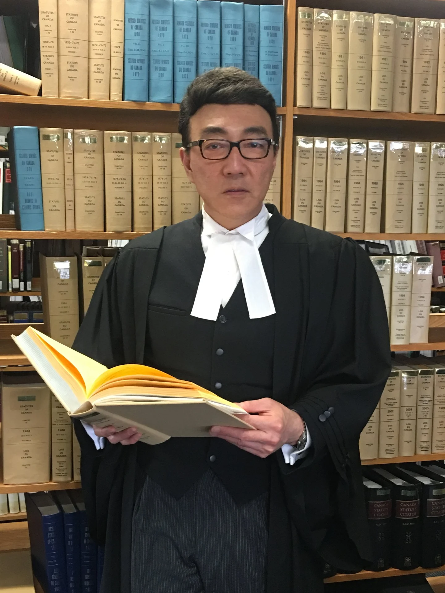 多伦多刑事律师 Patrick Sun 孙健铨身穿律师袍站在法律图书馆内